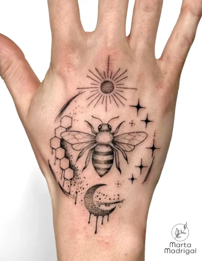 Tatouage d'une abeille, d'un rayon de miel et de la lune, sur la main, à Toulouse