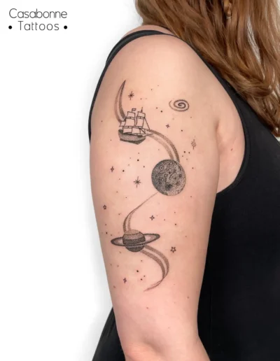 Tatouage ligne fine d'un bateau pirate, de planètes et d'étoiles, sur le bras, à Toulouse