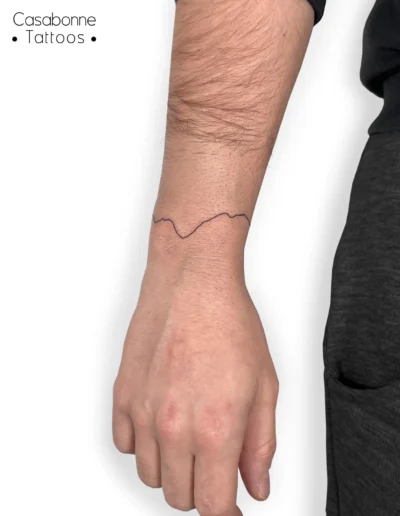 Tatouage ligne fine d'une chaîne de montagnes, sur le poignet, à Toulouse