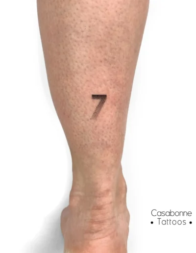 Petit tatouage du chiffre sept, sur la jambe, à Toulouse