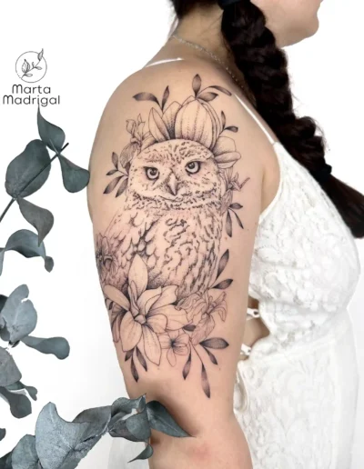 Tatouage d'une chouette parmi des fleurs, sur le haut du bras, à Toulouse