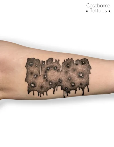 Tatouage dotwork d'un ciel étoilé façon peinture qui dégouline, sur l'avant-bras, à Toulouse