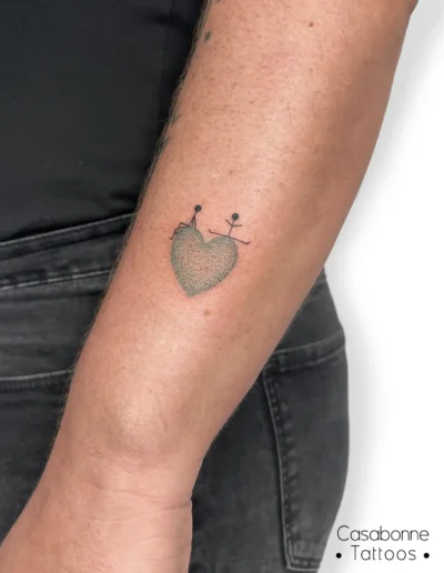 Tatouage d'un cœur avec de petits personnages, sur l'avant-bras, à Toulouse