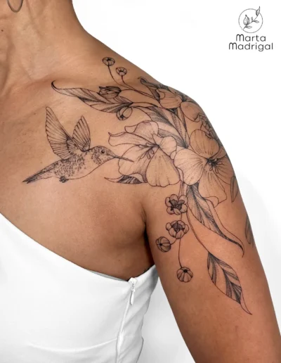 Tatouage d'un colibri parmi des fleurs, sur l'épaule, à Toulouse