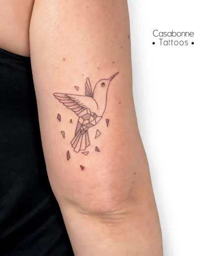 Tatouage ligne fine d'un colibri géométrique, sur le bras, à Toulouse