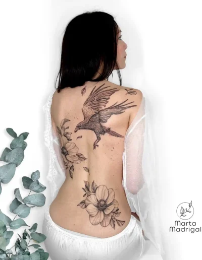 Tatouage d'un corbeau parmi des fleurs, sur le haut du dos, à Toulouse