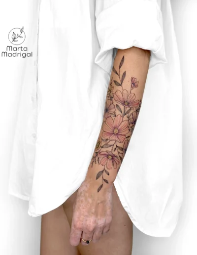 Tatouage floral colore (cosmos et bouton d'or) en couverture de cicatrice sur l'avant-bras, a Toulouse