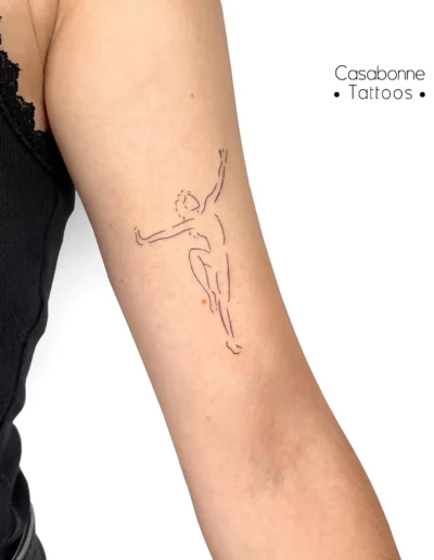 Tatouage ligne fine d'une danseuse africaine, sur le bras, à Toulouse