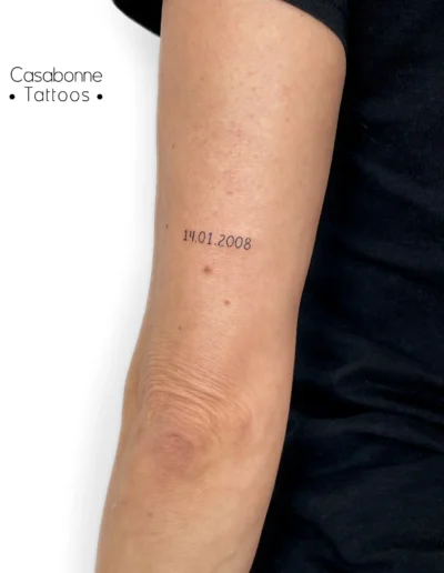 Tatouage d'une date de naissance, sur le bras, à Toulouse