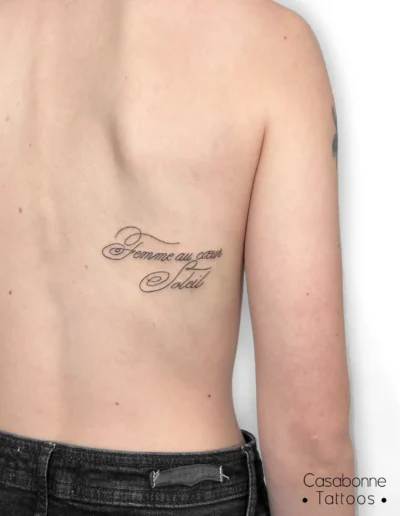 Tatouage de l'inscription 'Femme au cœur Soleil', sur le dos, à Toulouse