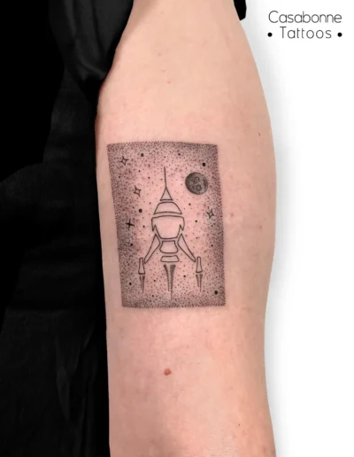 Tatouage dotwork d'une fusée et d'étoiles, sur le bras, à Toulouse
