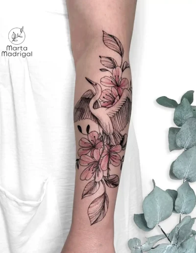 Tatouage d'une grue parmi des fleurs, sur l'avant-bras, à Toulouse