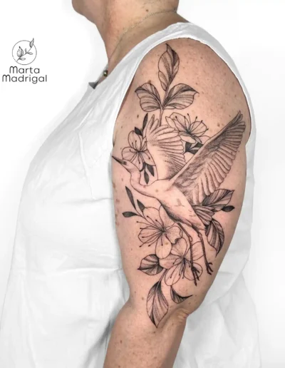 Tatouage d'une grue parmi des fleurs, sur le haut du bras, à Toulouse