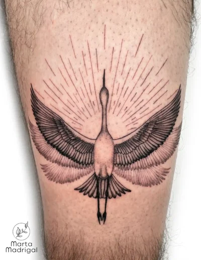 Tatouage d'une grue aux ailes déployées avec des rayons de soleil, sur la cuisse, à Toulouse