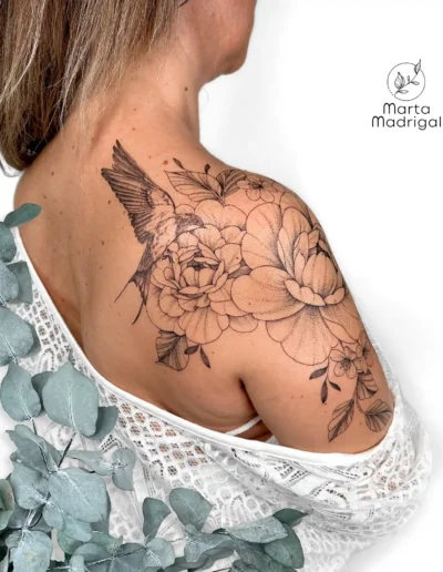 Tatouage d'une hirondelle parmi des fleurs, sur l'épaule et le dos, à Toulouse