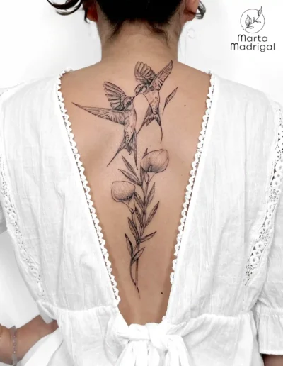 Tatouage de deux hirondelles parmi des fleurs, sur le haut du dos, à Toulouse