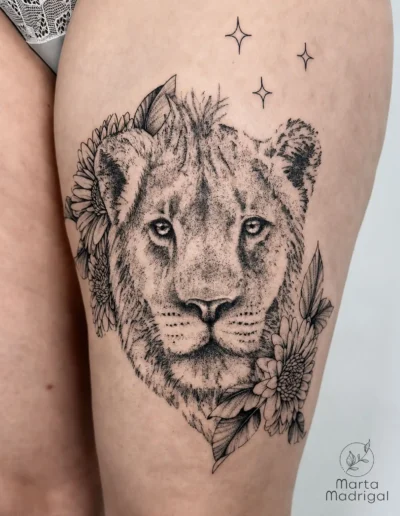 Tatouage réaliste d'une tête de lion parmi des fleurs, sur la cuisse, à Toulouse
