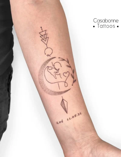 Tatouage ligne fine d'une lune, d'un cœur et d'une couronne végétale avec une date, sur l'avant-bras, à Toulouse