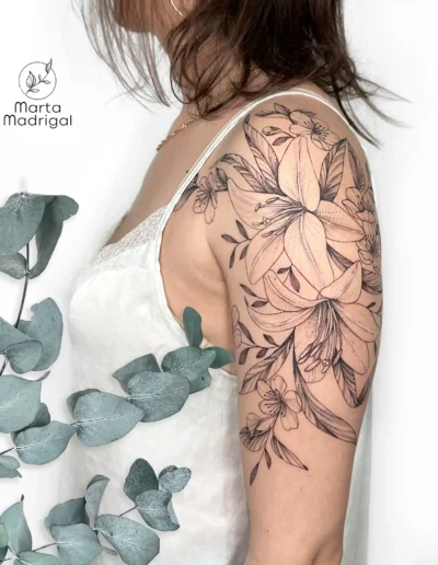 Tatouage de lys et de fleurs de cerisier sur le haut du bras, a Toulouse