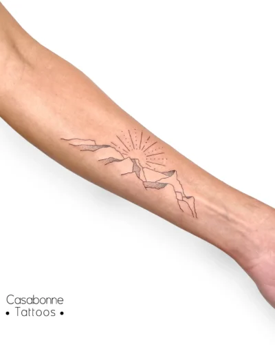 Tatouage dotwork d'une montagne avec un soleil, sur l'avant-bras, à Toulouse