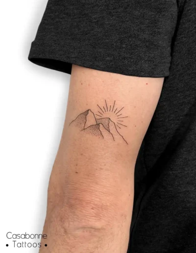 Tatouage dotwork de montagnes avec un soleil, sur l'avant-bras, à Toulouse