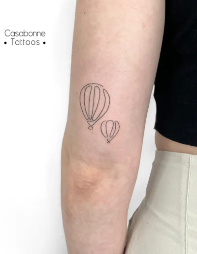 Tatouage ligne fine de deux montgolfières, sur le bras, à Toulouse