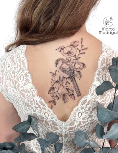 Tatouage d'un oiseau posé sur une branche fleurie, sur le dos, à Toulouse