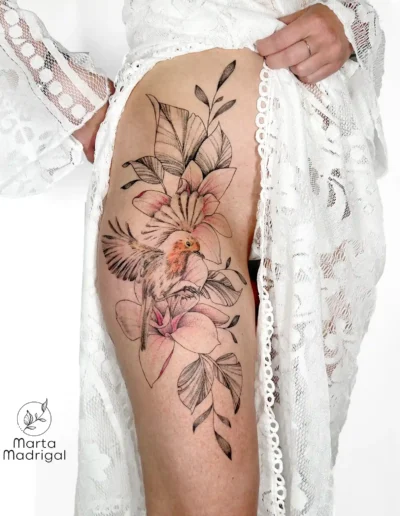 Tatouage couleur d'un oiseau parmi des fleurs, sur la hanche, à Toulouse