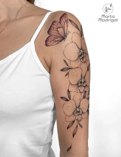 Tatouage d'un papillon et d'orchidées, sur le haut du bras, à Toulouse