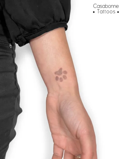 Petit tatouage d'une patte de chien, sur le poignet, à Toulouse