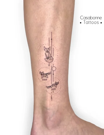 Tatouage de renards géométriques avec des dates, sur la jambe, à Toulouse