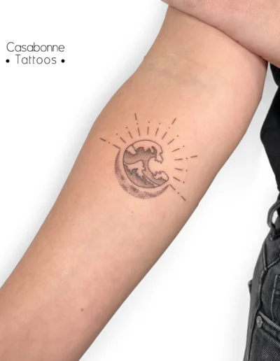 Tatouage dotwork d'un soleil, d'une vague et d'une lune, sur l'avant-bras, à Toulouse