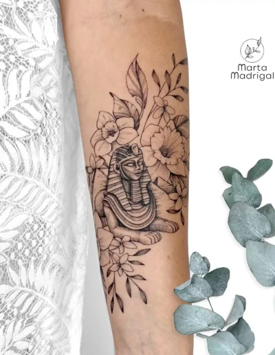 Tatouage d'un sphinx égyptien entouré de fleurs, sur l'avant-bras, à Toulouse