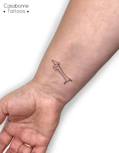 Tatouage ligne fine d'un teckel façon Picasso, sur le poignet, à Toulouse