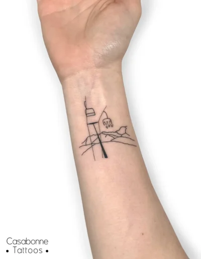 Tatouage ligne fine d'un télésiège, souvenir de Baqueira, sur le poignet, à Toulouse