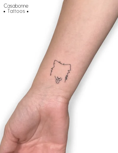 Tatouage ligne fine d'une tête de chien, sur le poignet, à Toulouse