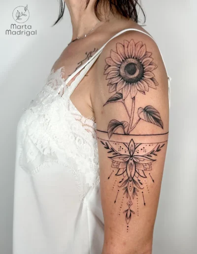 Tatouage tournesol et pendentif mandala sur le haut du bras, a Toulouse