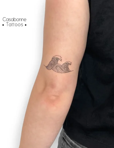 Tatouage ligne fine de vagues, sur le bras, à Toulouse