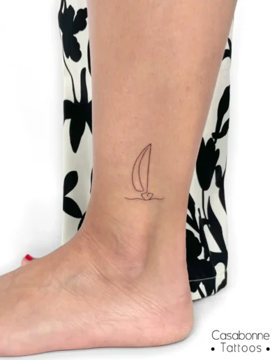 Tatouage ligne fine d'un voilier, sur la cheville, à Toulouse