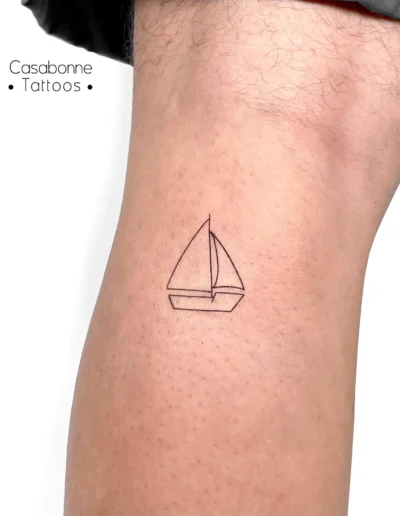 Tatouage ligne fine d'un voilier, sur la jambe, à Toulouse